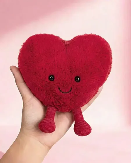 Peluche cœur macaron rouge, doux doudou gourmand avec visage souriant.